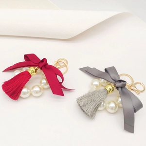 Detailed view of red and grey pearl ring keychains with ribbon bows and tassels