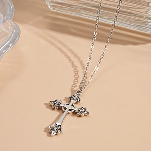 Close-up of vintage silver cross necklace with intricate gothic relief patterns on the pendant