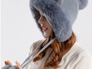 Close-up of grey knitted winter hat with plush lining and faux fur pompom details