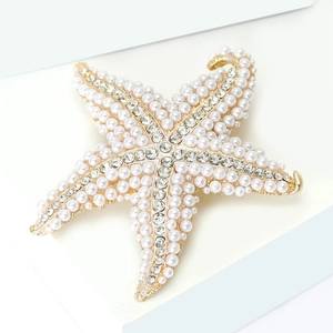 Detailed close-up of a starfish brooch with golden base, faux pearls and rhinestones