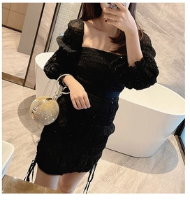 Detail of elegant black puff sleeve dress with ruched drawstring and gold spherical clutch