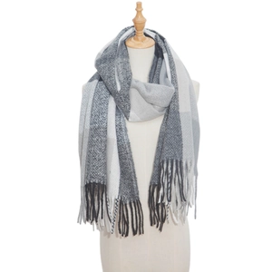 Detail of grey and white plaid thick scarf with long tassels on a beige mannequin