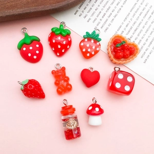 Macro detail of red resin strawberry and mushroom DIY jewelry pendants and charms