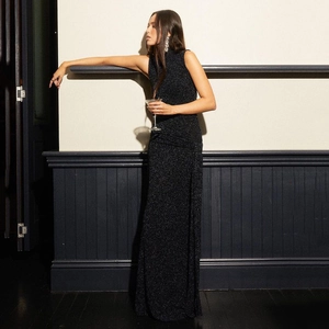 Elegant sleeveless black glitter maxi dress worn by a model in a sophisticated dinner setting