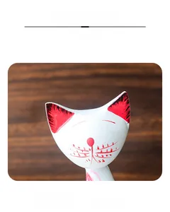 Close-up of hand-painted cat ornament featuring red ear details and minimalist white finish