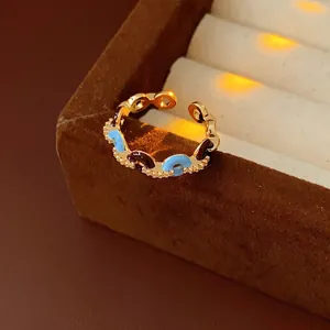 Golden adjustable chain ring with blue enamel and zircon on a velvet jewelry box