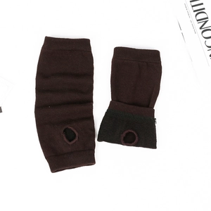 Detail view of dark brown knitted arm warmers with thumb holes and fine ribbed texture