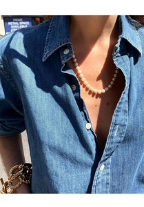 Detail of vintage layered pearl necklace and chunky gold bracelet worn on denim