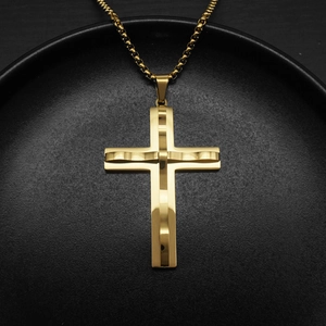 Close-up of a minimalist golden cross pendant necklace resting on a dark plate