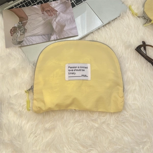 Close-up of bright yellow nylon cosmetic pouch with woven label on a plush background