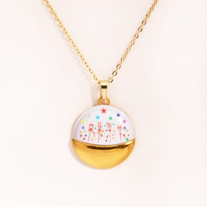 Detail shot of the golden round pendant necklace featuring colorful star and enamel patterns