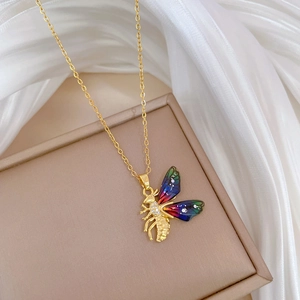 Close-up of golden butterfly pendant with colorful enamel wings and pave zircon details
