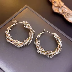 Luxury gold twisted hoop earrings with micro-paved zircons on a premium display box