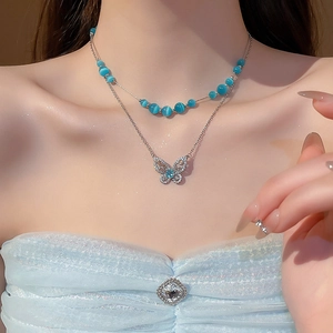Detailed view of silver butterfly pendant with blue zircon stones and opal beads