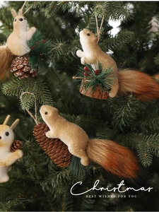 Detail of plush squirrel ornaments with fluffy tails hanging on a green Christmas tree