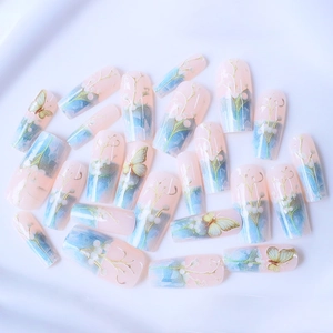 Faux ongles dégradé rose et bleu avec motifs de muguet et éléments de papillon