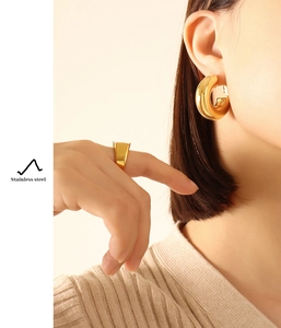 Macro shot of polished gold stainless steel hoop earrings and matching wide band ring