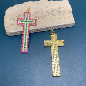 Detail of 18k gold cross pendants with pink and green zircon stones on stone base