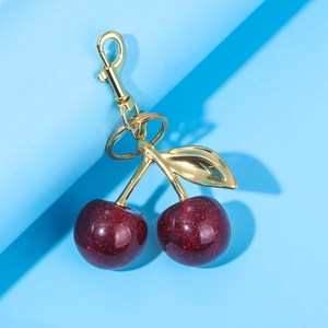 Macro detail of deep red glitter cherry keychain with gold leaf and lobster clasp
