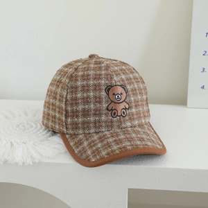 Detail of plaid wool baseball cap featuring intricate cartoon bear embroidery and trim
