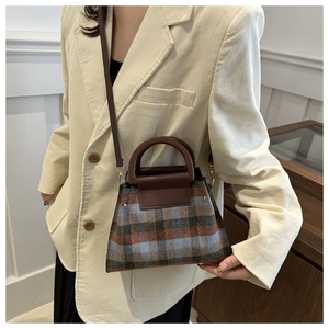 Sac bandoulière vintage à carreaux avec cuir marron et détails dorés porté par un mannequin