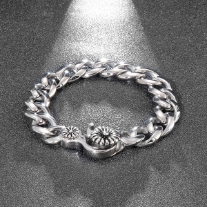 Makro-Detail des silbernen Titanstahl-Cuban-Armbands mit Gänseblümchen-Verschluss