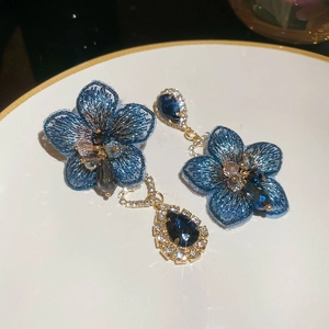Dettaglio orecchini a fiore ricamato blu con cristalli a goccia e finiture in metallo dorato