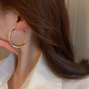 Close-up of elegant gold polished geometric hoop earring worn by a model in a minimal setting