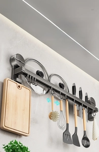 Macro detail of multi-functional kitchen suction cup wall rack with utensils and pot lids
