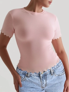 Detail of a pink yoga t-shirt featuring elegant scalloped edges on sleeves and hem