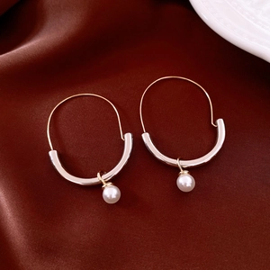 Detailed view of U-shaped gold earrings with pearls on red silk background