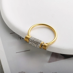 Detail shot of a luxury gold band ring featuring a rotatable crystal paved cylinder charm