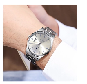Close-up of a men's silver steel strap quartz watch on a wrist in a modern office