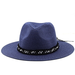 Close-up of navy blue woven fedora hat with ornate beaded band on white background
