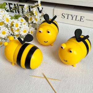 Trois porte-cure-dents créatifs en forme d'abeille jaune et noire sur un bureau
