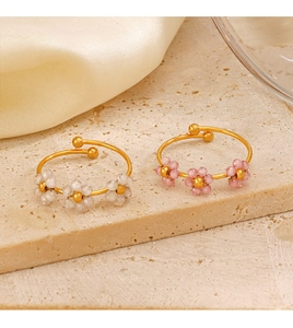 Detail of adjustable gold rings with delicate pink and white beaded flower designs