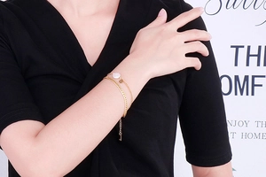 Detail of gold double-layered shell bracelet with white round pendant and flower charm