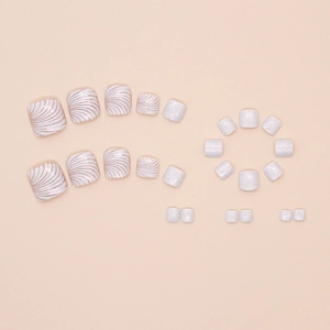 Detailed flat lay of pearl white press-on toenails with shell textures and fine glitter