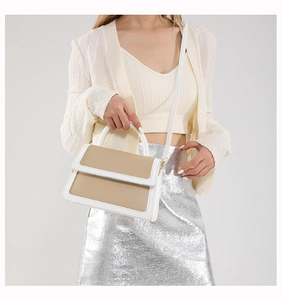 Modern two-tone crossbody bag in white and khaki faux leather worn by a model