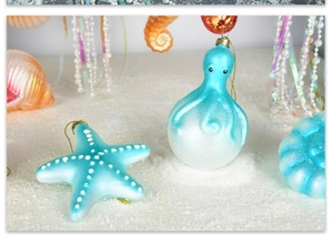 Marine Christmas ornaments featuring blue octopus, starfish, and shells on white sand