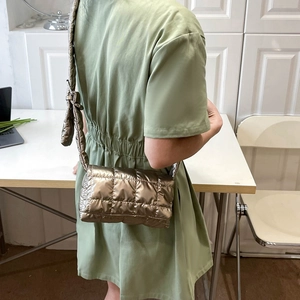 Quilted bronze metallic crossbody bag with adjustable strap worn by a model in interior