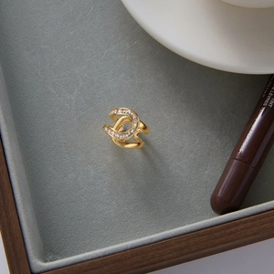 Détail d'une bague double C dorée avec zircons blancs sur un plateau en velours