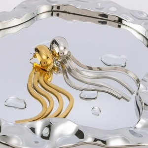 Elegant 18k gold and silver egg-shaped earrings with snake chain tassels on silver tray