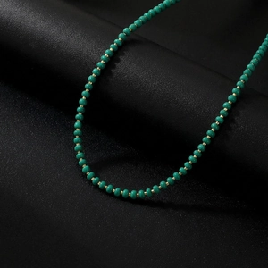 Macro detail of handmade emerald green beaded necklace with gold metal spacers