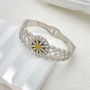 Detail of titanium steel bangle with heart cutouts and white daisy pendant charm