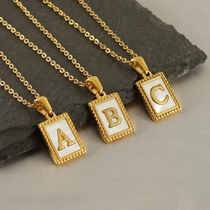 Detail von drei goldenen Buchstaben-Halsketten mit Perlmutt-Anhängern in Gold A B C