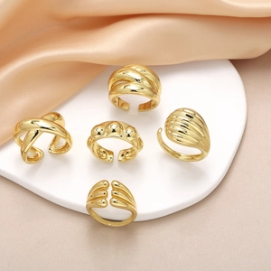 Set of five irregular polished gold plated open rings displayed on a white stand