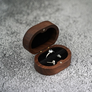 Oval walnut wood jewelry box with black velvet lining showing ring and clover earrings