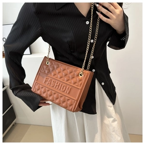 Brown crossbody bag with embossed FASHION lettering and gold chain strap on model