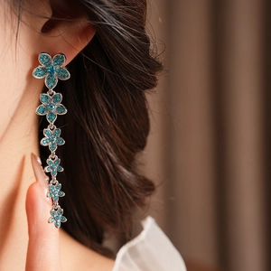 Gros plan de boucles d'oreilles fleurs vintage argentées avec zircons bleus sur un mannequin